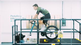 A white man rides a static bike in a lab