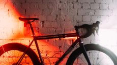 A bike against a whitewashed brick wall with bright red lights on at the back and a bright white light at the front